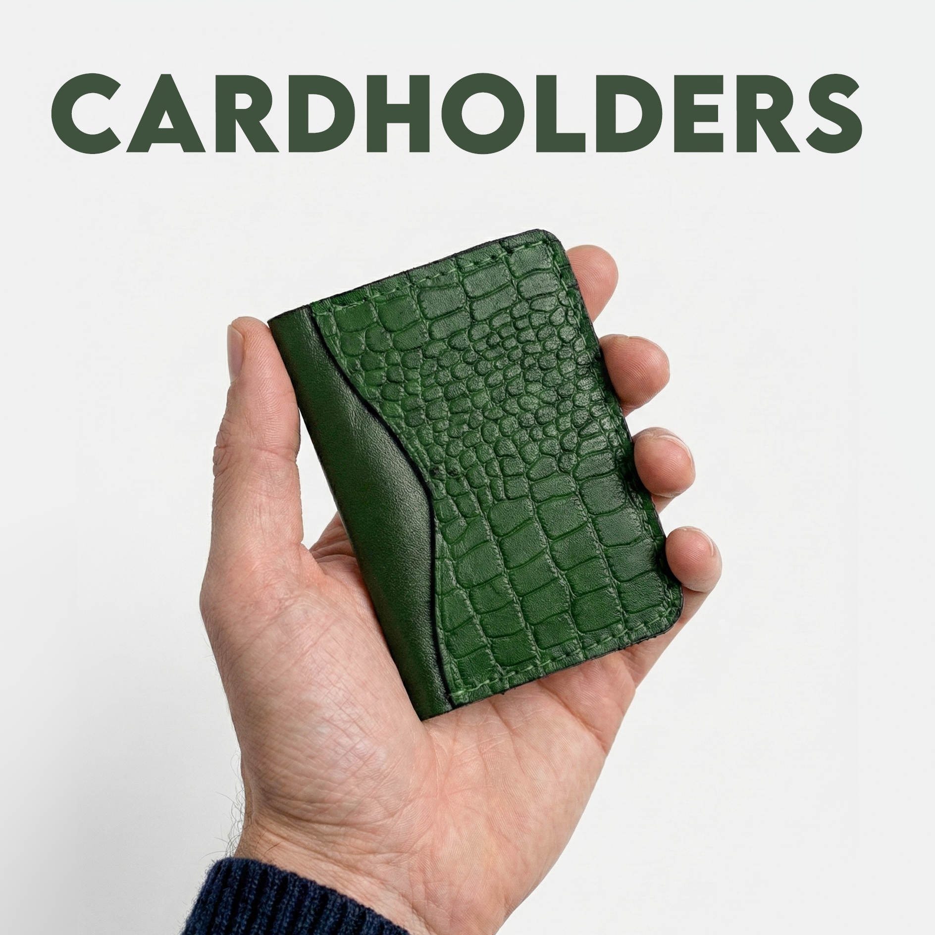 A hand holds a green, textured cardholder with a crocodile pattern against a light background. Bold text above reads "CARDHOLDERS." Elegant, stylish tone.