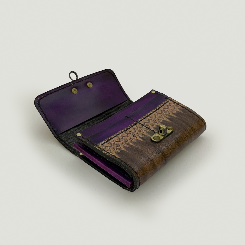 Open brown handmade leather wallet with purple interior on a light gray background