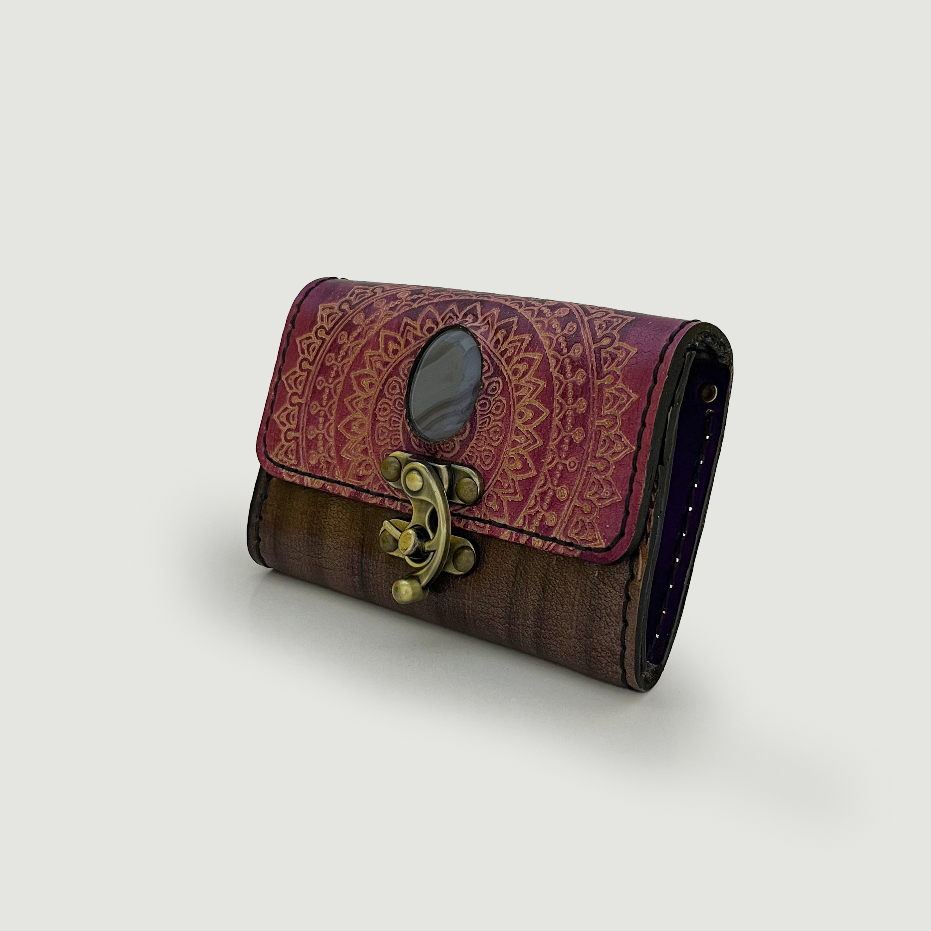 handmade clutch with decorative pattern and gold clasp on a light gray background