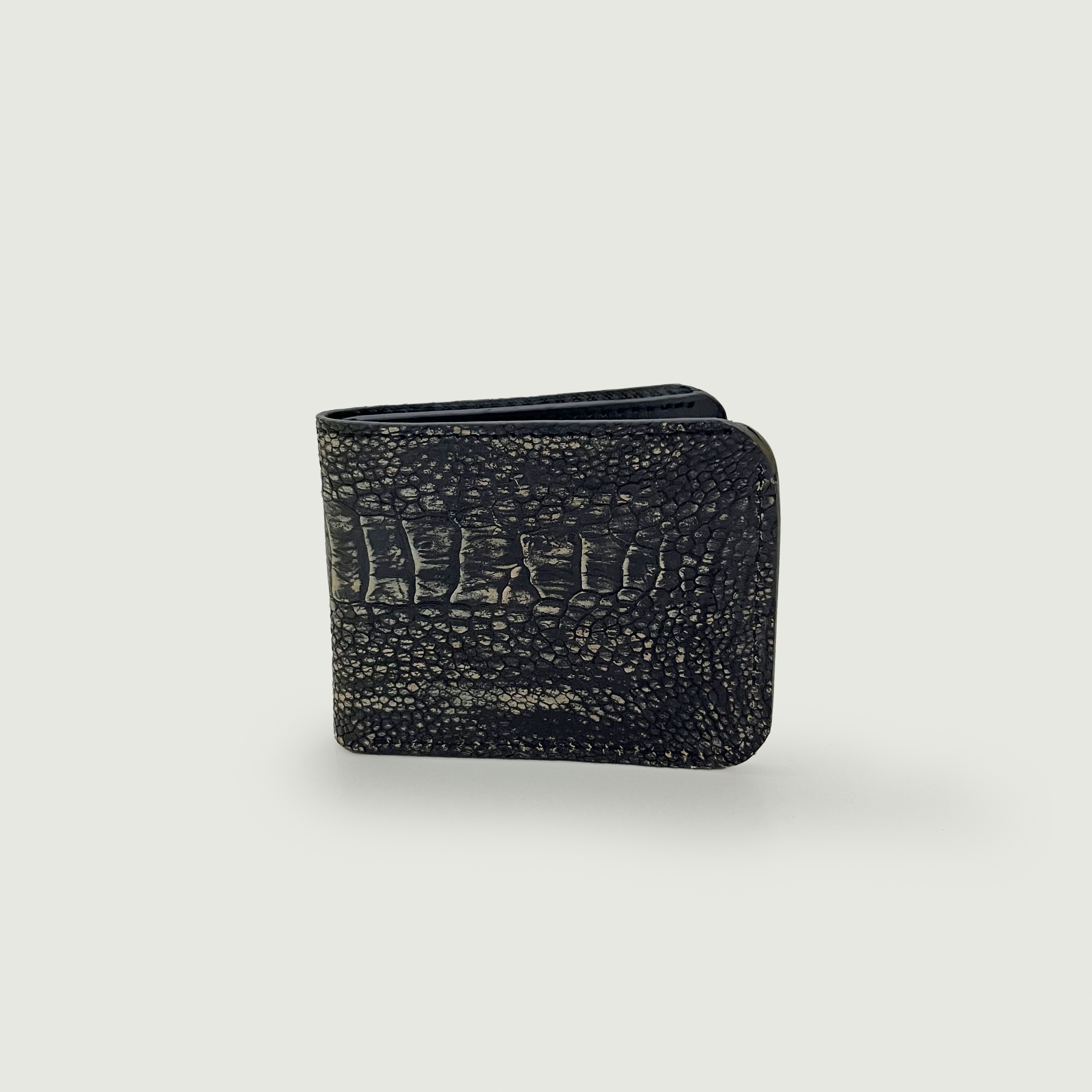 Black textured wallet with an embossed crocodile skin pattern against a light gray background, conveying a sense of luxury and sophistication.